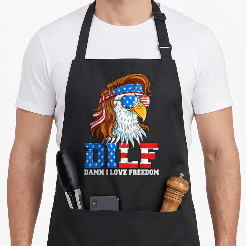 Dilf eagles grill apron - Cartoon eagle with brown hair, star-spangled sunglasses, and DILF text — shown on a black cotton canvas apron against a white background