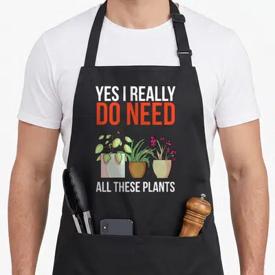 Plant gardening do i need an apron - Three cartoon potted plants with text Yes I Really Do Need All These Plants — shown on a black cotton canvas apron against a white background