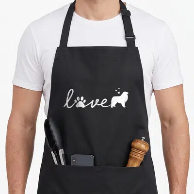 Pyr dog apron - White script love with paw print, dog silhouette, and three hearts — shown on a black cotton canvas apron against a white background