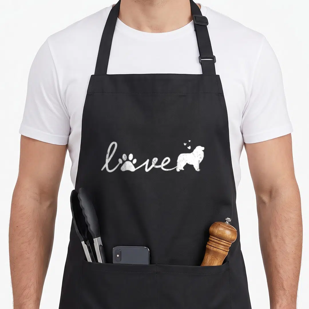 Pyr dog apron - White script love with paw print, dog silhouette, and three hearts — shown on a black cotton canvas apron against a white background