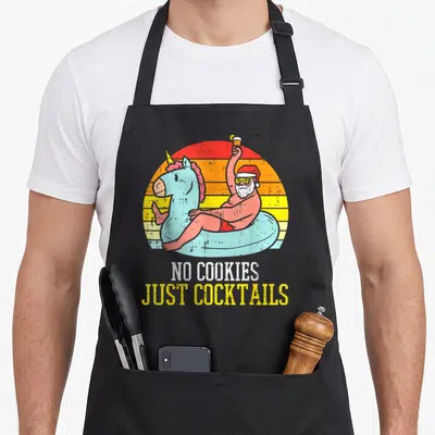 Cocktail women's christmas aprons - Stacked text reading NO COOKIES JUST COCKTAILS in distressed white and yellow fonts — shown on a black cotton canvas apron against a white background
