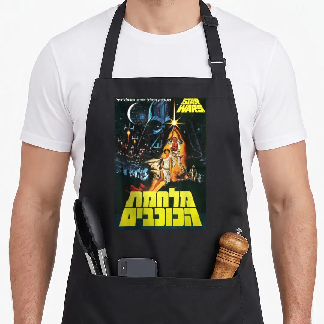 Hope hebrew aprons - Star Wars poster with Luke Skywalker, Vader helmet, robots, and yellow Hebrew text — shown on a black cotton canvas apron against a white background