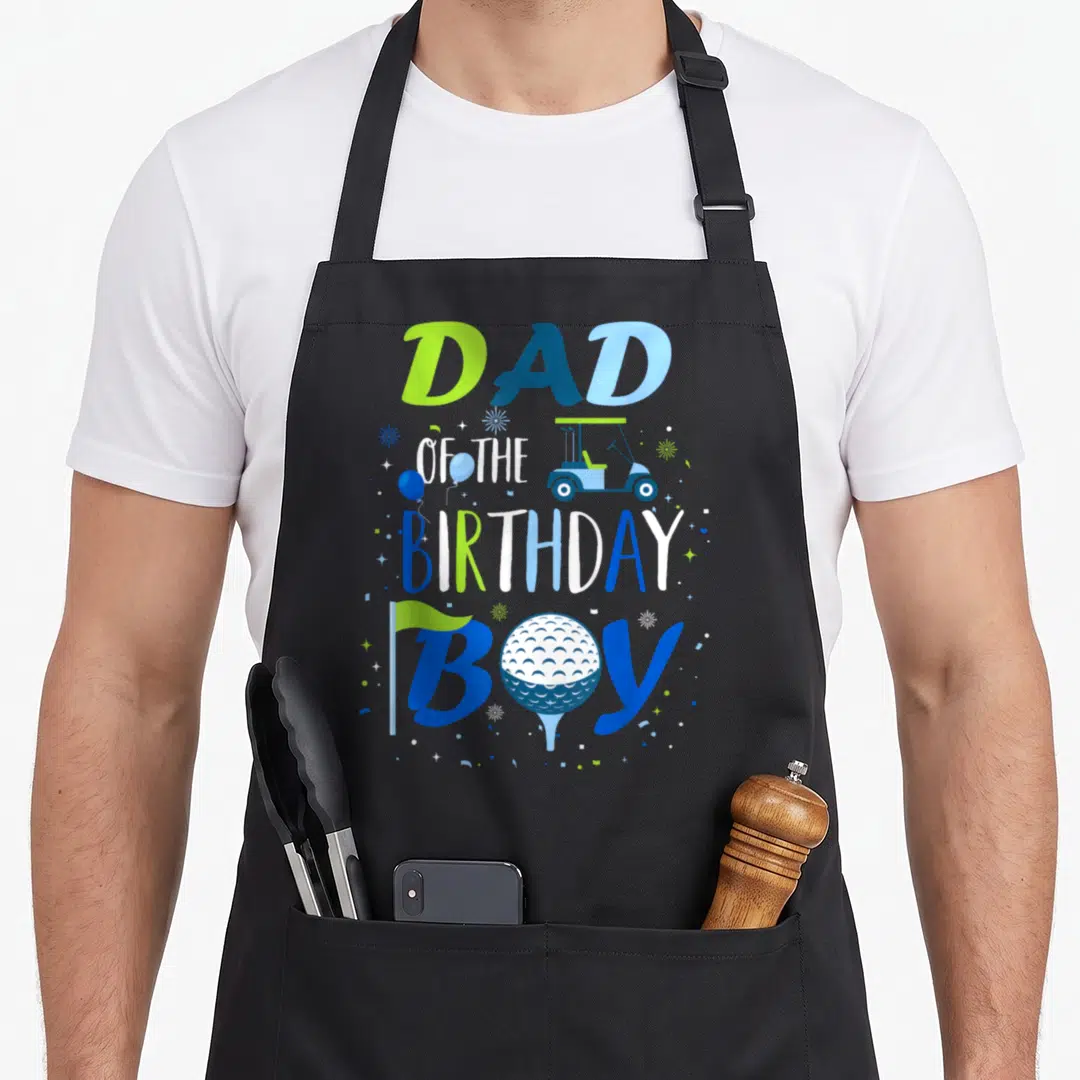 Birthday golf apron - DAD OF THE BIRTHDAY BOY text with golf cart, ball, flag, and confetti in blue and green — shown on a black cotton canvas apron against a white background