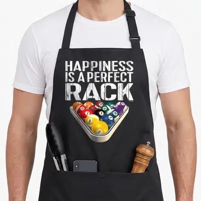 Perfect billiards apron - HAPPINESS IS A PERFECT RACK text above triangular rack of colored billiard balls — shown on a black cotton canvas apron against a white background