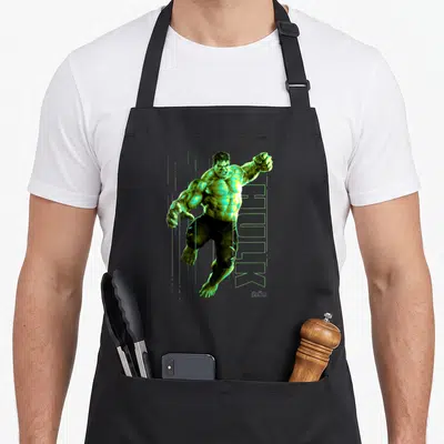 Jump infinity apron - Realistic green Hulk figure jumping over vertical HULK text with Avengers logo in corner — shown on a black cotton canvas apron against a white background