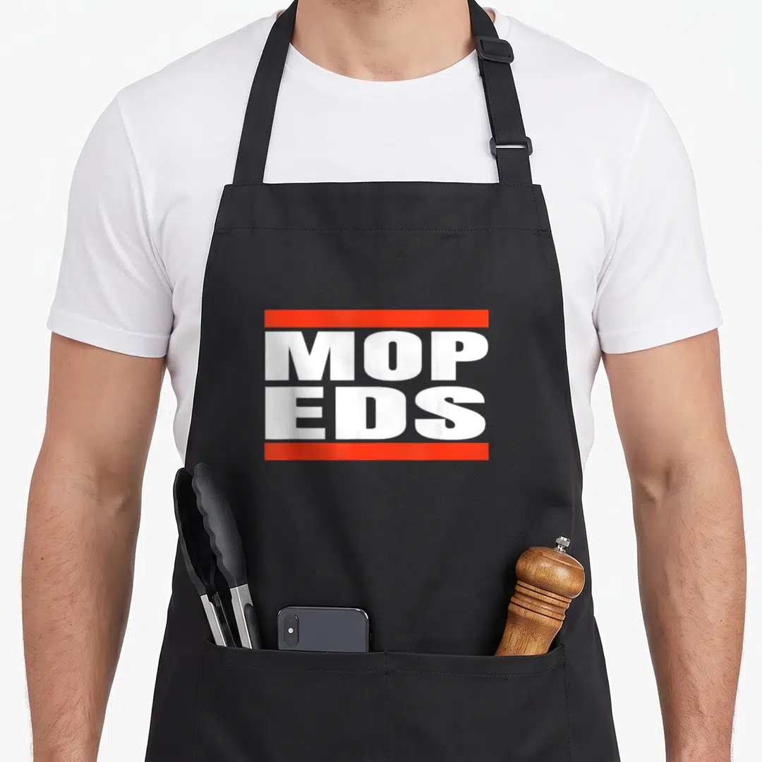Cute moped girl apron - White MOPEDS text between two red horizontal bars on grey background — shown on a black cotton canvas apron against a white background