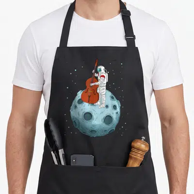 Bass double apron - Astronaut playing brown double bass on light blue cratered moon with scattered stars — shown on a black cotton canvas apron against a white background