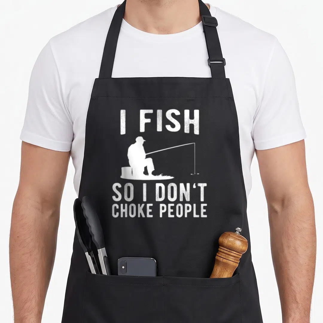 Choke fish apron - White text I FISH SO I DON'T CHOKE PEOPLE surrounding a seated fisherman silhouette — shown on a black cotton canvas apron against a white background