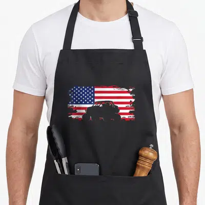 Road american flag apron - Grey off-road vehicle silhouette over distressed red white and blue USA flag — shown on a black cotton canvas apron against a white background