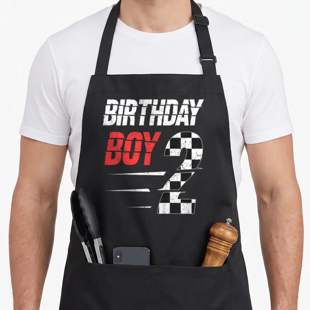 Birthday racing 2nd apron - Checkered number 2 with speed lines and BIRTHDAY BOY text in distressed style — shown on a black cotton canvas apron against a white background