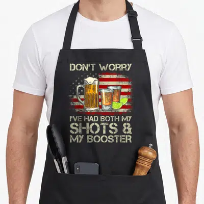 Worry american flag apron - Beer mug, two shot glasses with lime slices in front of a distressed American flag — shown on a black cotton canvas apron against a white background