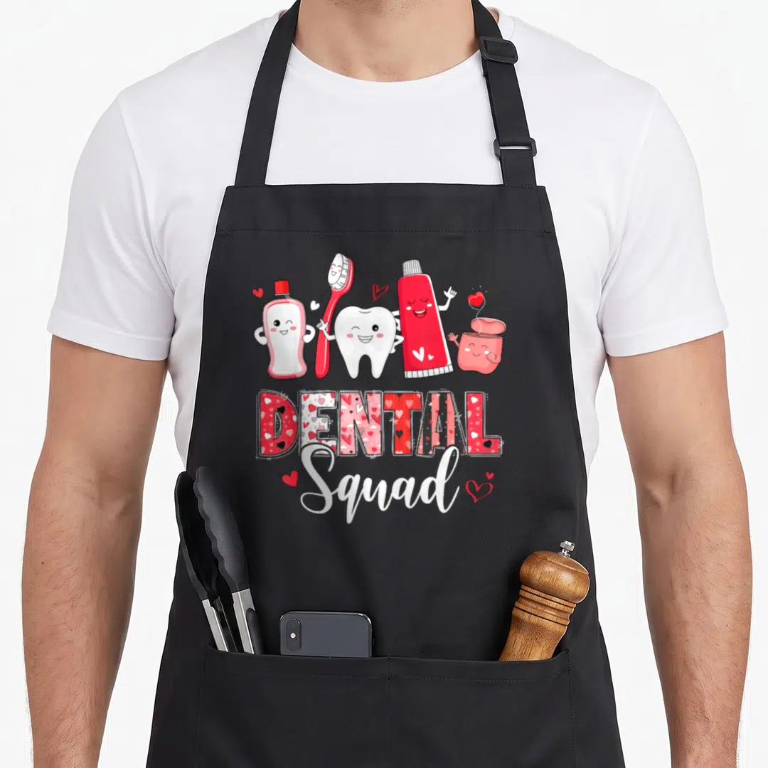 Dental valentine's day apron - Cartoon toothbrush, tooth, and toothpaste characters above patterned DENTAL Squad text — shown on a black cotton canvas apron against a white background