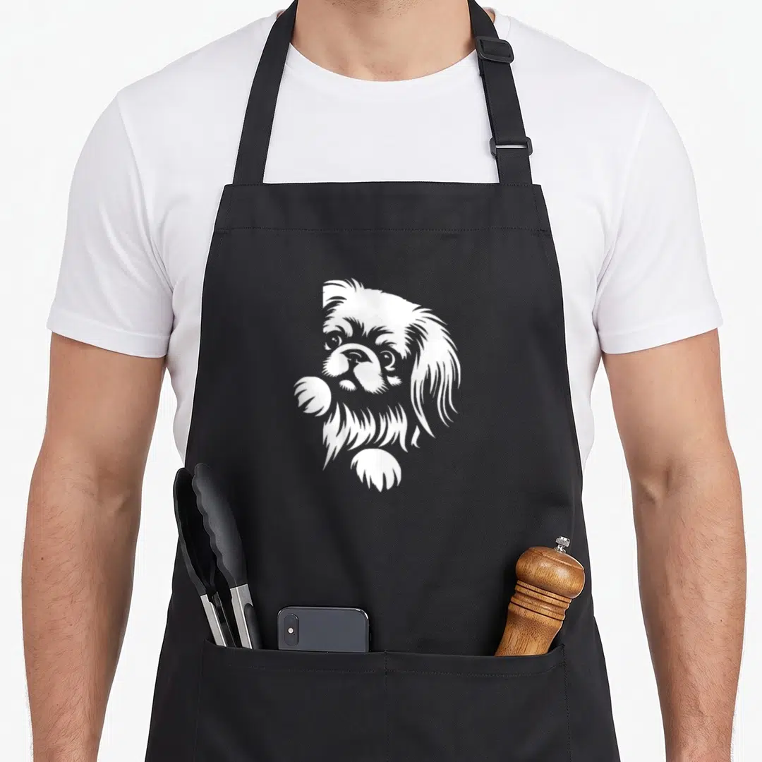 Pekingese peeking dog apron - White line art of a Pekingese dog head and paws peeking over an edge — shown on a black cotton canvas apron against a white background