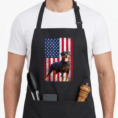 Dog 4th of july apron - Rottweiler photo standing in front of a distressed red white and blue American flag background — shown on a black cotton canvas apron against a white background