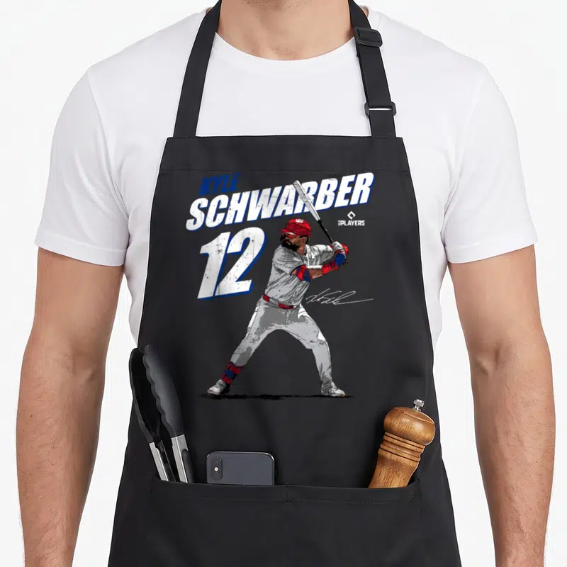Kyle baseball apron - Baseball player in batting stance with KYLE SCHWARBER 12 text in red white blue — shown on a black cotton canvas apron against a white background