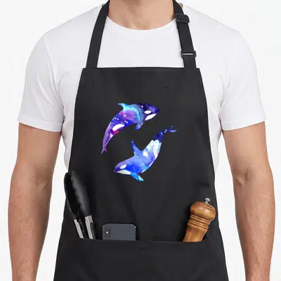 Orca couple apron - Two leaping orcas in blue purple white watercolor circular design — shown on a black cotton canvas apron against a white background