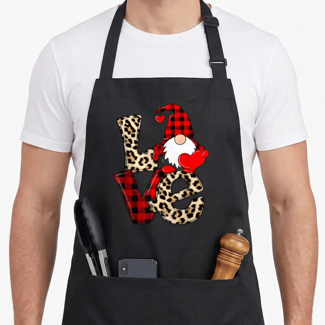 Gnome leopard apron - Cartoon gnome holding red heart on LOVE letters with leopard and plaid fills — shown on a black cotton canvas apron against a white background