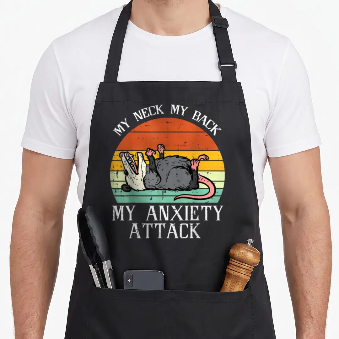 Opossum song days apron - Retro striped sun with screaming opossum lying on back and white text reading MY NECK MY BACK — shown on a black cotton canvas apron against a white background