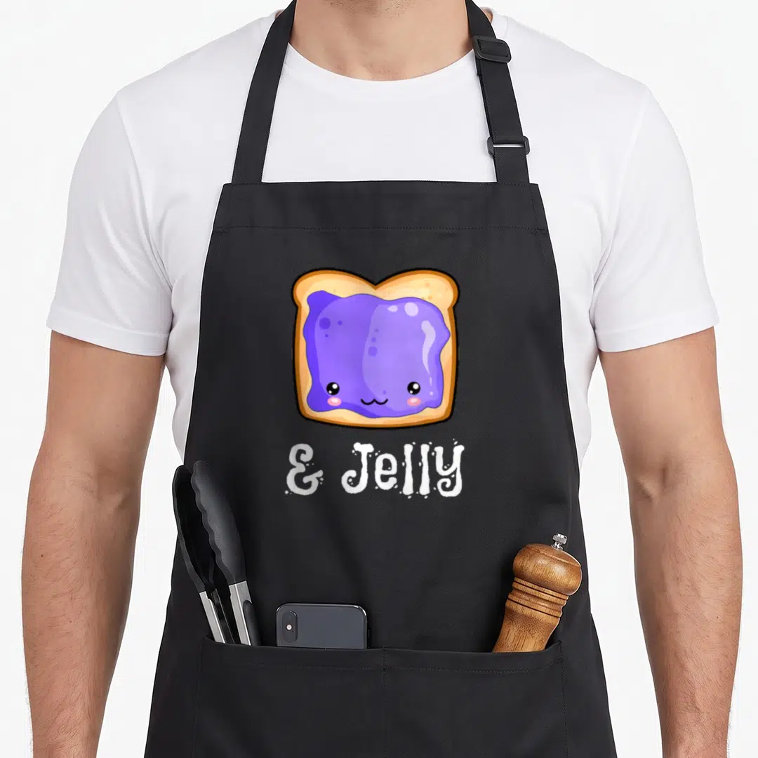 Peanut kawaii apron - Cartoon toast with purple jelly and white & Jelly text on black background — shown on a black cotton canvas apron against a white background