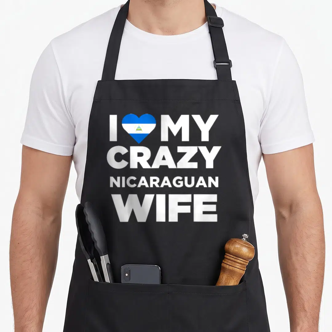 Nicaragua wife apron - White stacked text I MY CRAZY NICARAGUAN WIFE with blue white flag heart replacing love — shown on a black cotton canvas apron against a white background