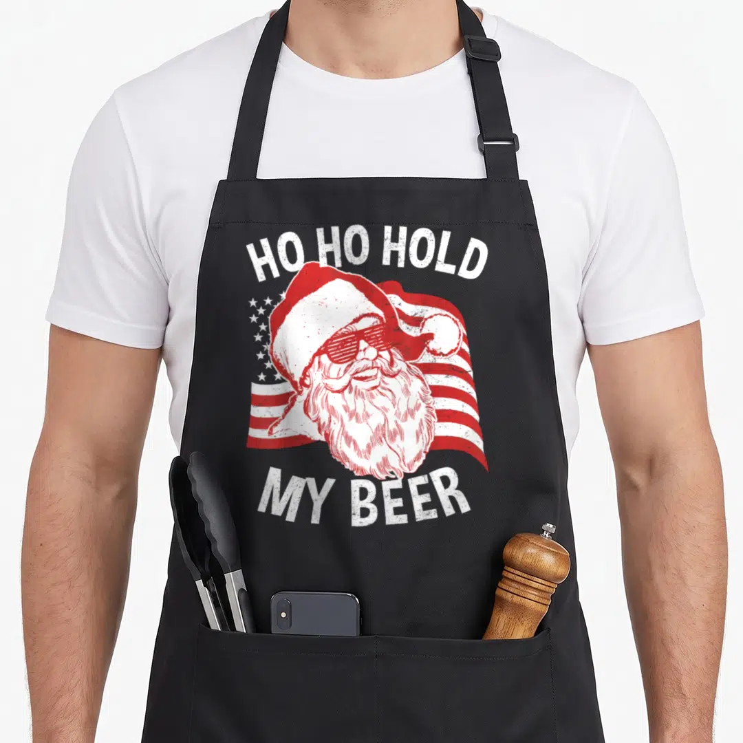 Christmas beer apron - Santa in sunglasses with US flag and Ho Ho Hold My Beer text — shown on a black cotton canvas apron against a white background