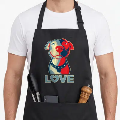 Pitbull writing lover apron - Stylized dog head in red, blue, beige with heart collar and LOVE text below — shown on a black cotton canvas apron against a white background