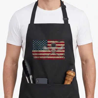 Jersey american flag apron - Distressed flag with white lacrosse helmet and two crossed sticks — shown on a black cotton canvas apron against a white background