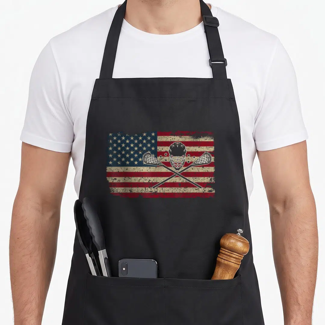 Jersey american flag apron - Distressed flag with white lacrosse helmet and two crossed sticks — shown on a black cotton canvas apron against a white background