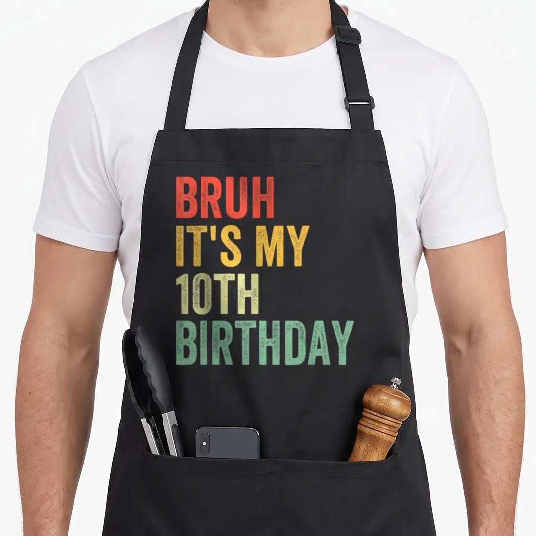 Retro bruh birthday apron - Stacked text BRUH IT'S MY 10TH BIRTHDAY in red yellow beige and green block letters — shown on a black cotton canvas apron against a white background