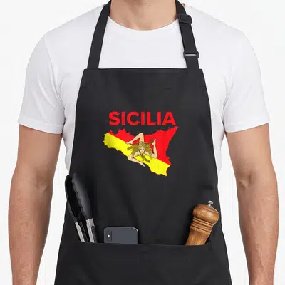 Sicilian pride sicily apron - Red and yellow Sicily map with Trinacria woman and SICILIA text — shown on a black cotton canvas apron against a white background