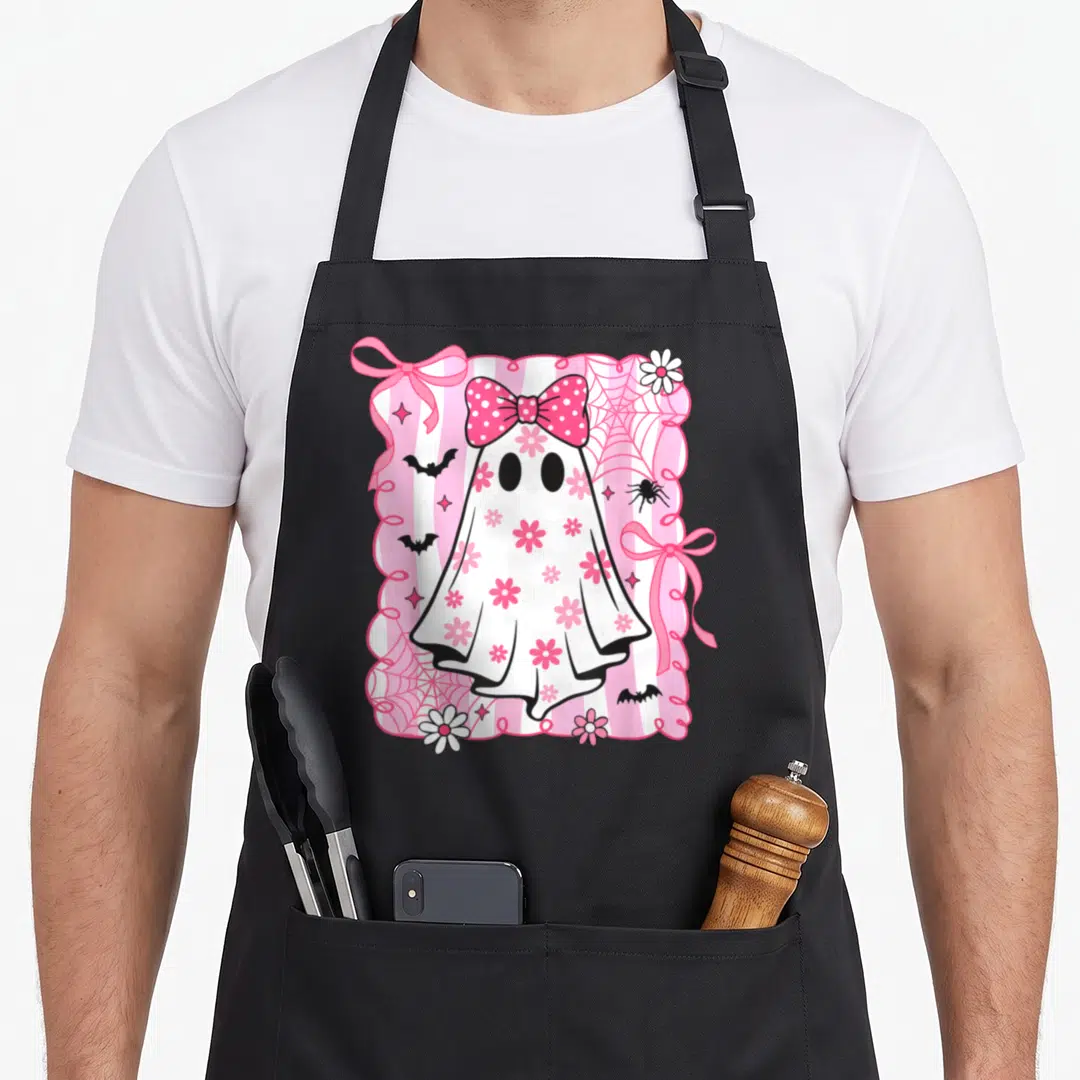 Preppy halloween apron - Cartoon ghost with pink bow, flowers, bats, and spider webs on pink and white stripes — shown on a black cotton canvas apron against a white background