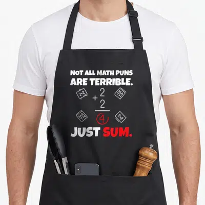Terrible teacher apron - Not All Math Puns Are Terrible Just Sum text with 2+2=4 equation and book icons — shown on a black cotton canvas apron against a white background