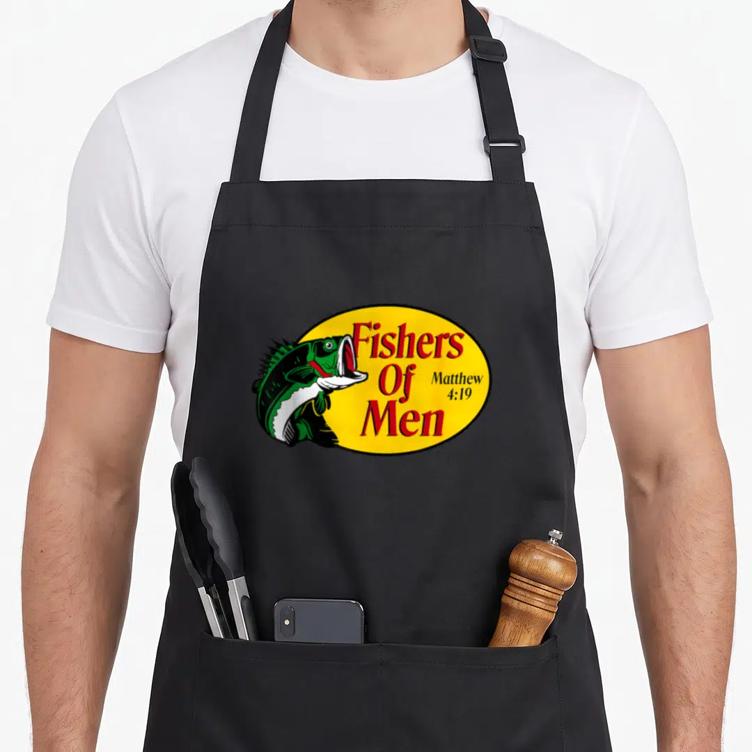Fisher fishing aprons - Green cartoon fish overlapping yellow oval with red Fishers Of Men text — shown on a black cotton canvas apron against a white background