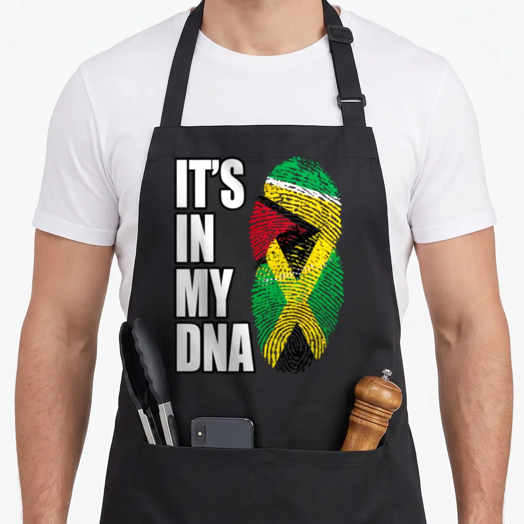 Jamaican guyanese heritage aprons - IT'S IN MY DNA text beside a fingerprint patterned with Jamaican and Guyanese flag — shown on a black cotton canvas apron against a white background