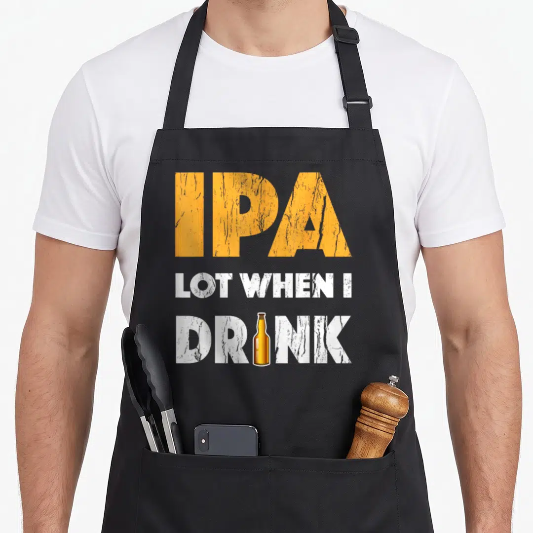 Lot drink beer apron - Distressed orange IPA text above white LOT WHEN I DRINK with brown bottle replacing letter I — shown on a black cotton canvas apron against a white background