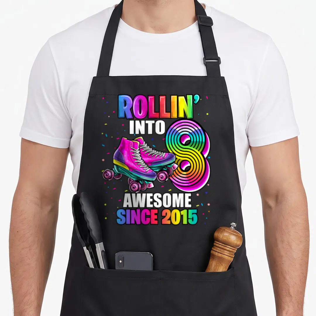 Skating 8th birthday apron - Rainbow roller skates and number 8 with confetti and text Rollin into Awesome Since 2015 — shown on a black cotton canvas apron against a white background