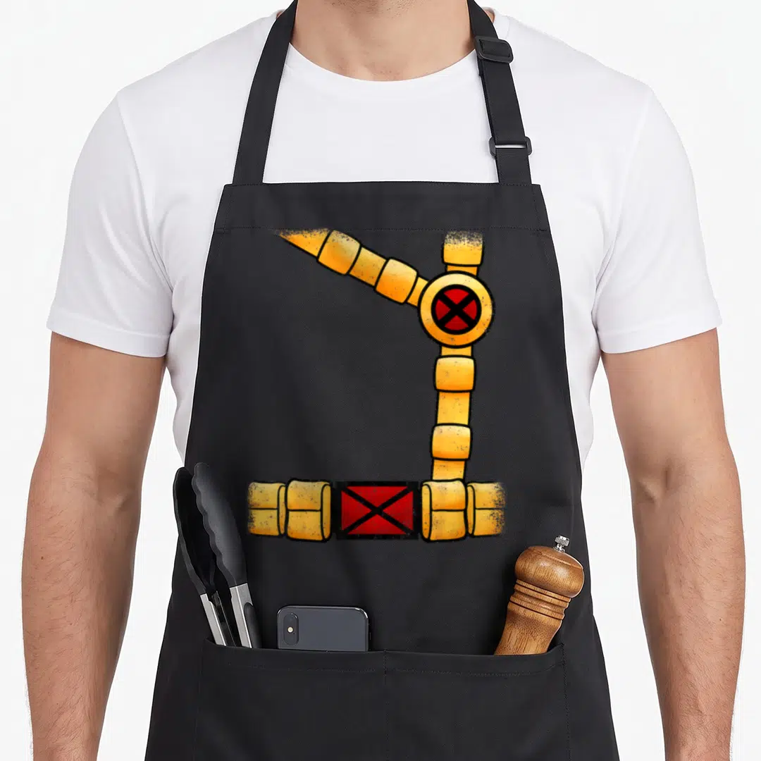 Cyclop x apron - Yellow segmented mechanical arm in L-shape with red cross symbols at joints, cartoon style — shown on a black cotton canvas apron against a white background