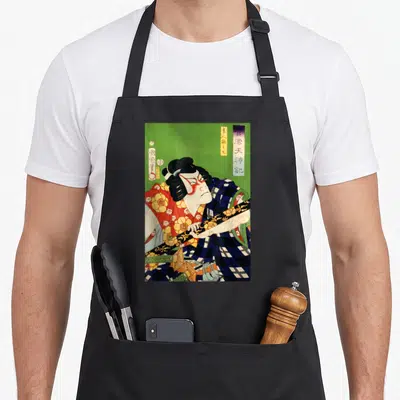 Japanese antique apron - Kabuki actor holding sword diagonally on green background with vertical Japanese text — shown on a black cotton canvas apron against a white background