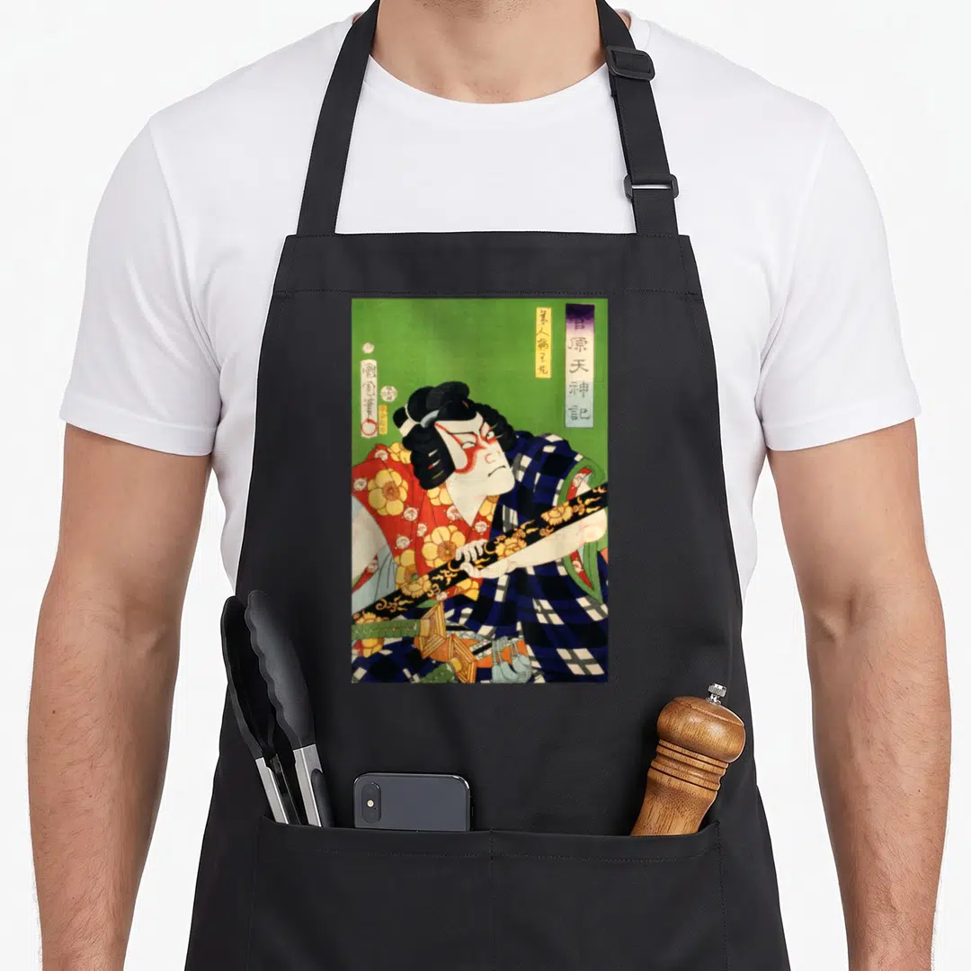 Japanese antique apron - Kabuki actor holding sword diagonally on green background with vertical Japanese text — shown on a black cotton canvas apron against a white background