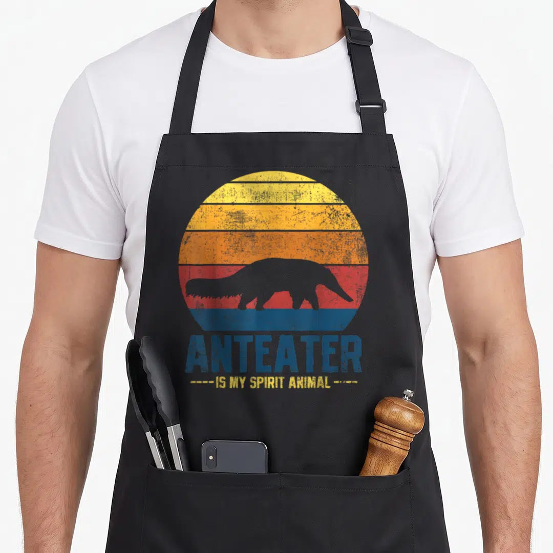 Vintage anteater apron - Grey anteater silhouette inside blue yellow orange red striped circle with printed text — shown on a black cotton canvas apron against a white background