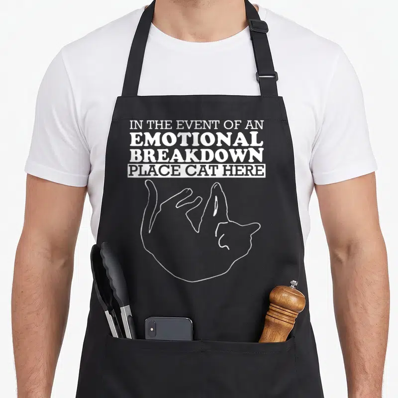 Kitty apron - White text and curled cat outline on black bib apron — shown on a black cotton canvas apron against a white background