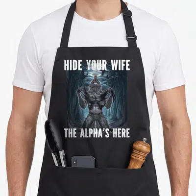 Alpha meme apron - Werewolf tearing shirt in forest with HIDE YOUR WIFE THE ALPHA'S HERE text — shown on a black cotton canvas apron against a white background