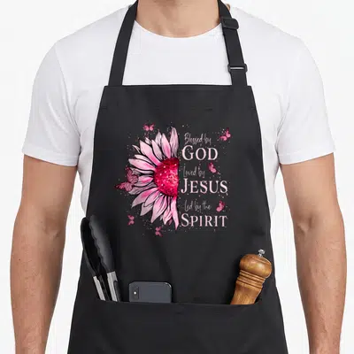 Blessed sunflower apron - Pink watercolor sunflower with butterflies and text Blessed by God Loved by Jesus Led — shown on a black cotton canvas apron against a white background