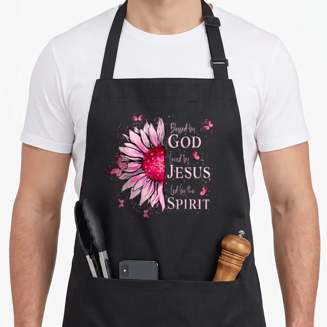 Blessed sunflower apron - Pink watercolor sunflower with butterflies and text Blessed by God Loved by Jesus Led — shown on a black cotton canvas apron against a white background