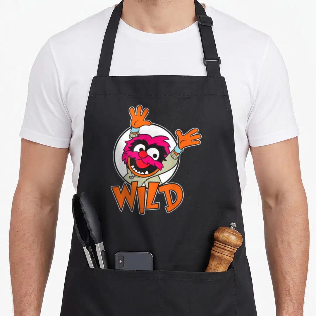 Baby animal apron - Pink cartoon creature with raised orange hands inside white circle, WILD text below — shown on a black cotton canvas apron against a white background