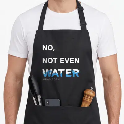 Even ramadan apron - White and blue typography reading No Not Even Water with splash graphics and hashtag Ramadan — shown on a black cotton canvas apron against a white background