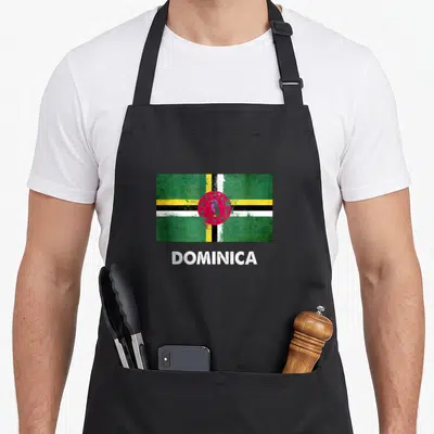 Dominica dominican republic apron - Distressed flag of Dominica with green red yellow white cross and central parrot — shown on a black cotton canvas apron against a white background