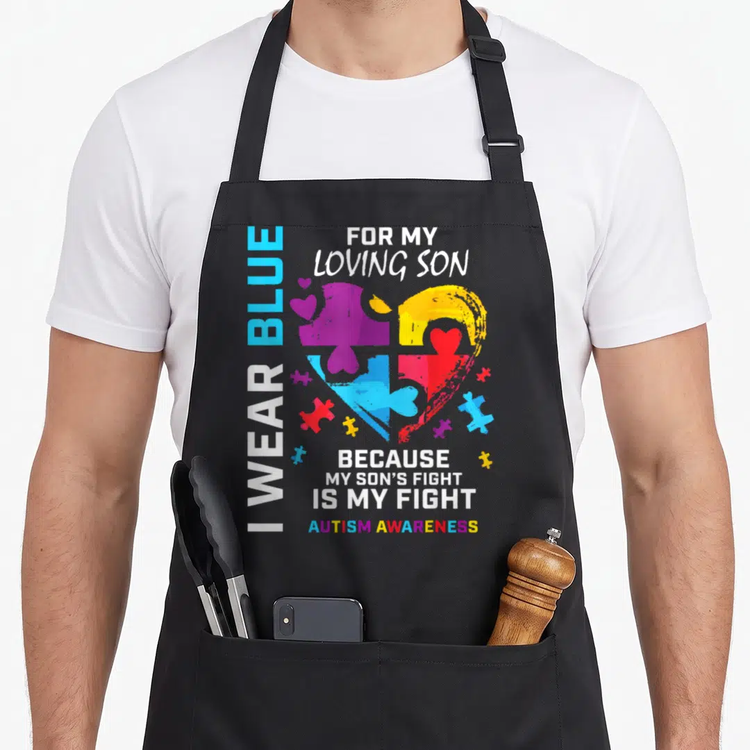 Puzzle dad and son aprons - Multi-colored puzzle heart with I Wear Blue text and Autism Awareness slogan — shown on a black cotton canvas apron against a white background
