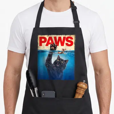 Parody kitten apron - Red PAWS text above black cat reaching from blue water for mouse — shown on a black cotton canvas apron against a white background