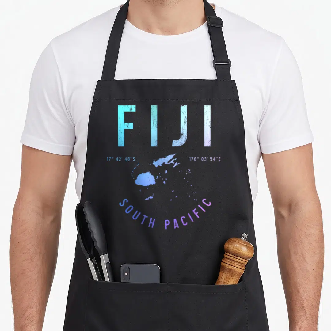 Souvenir fiji apron - Distressed FIJI map print with coordinates and SOUTH PACIFIC text in blue and purple — shown on a black cotton canvas apron against a white background